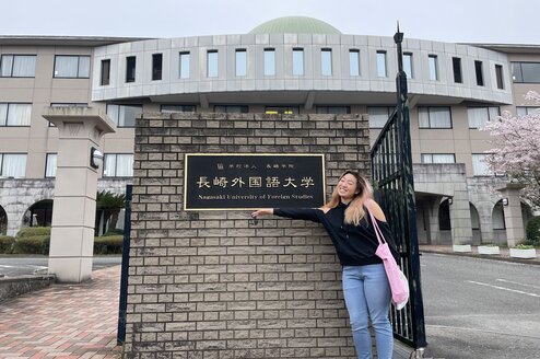Student pointing to university sign